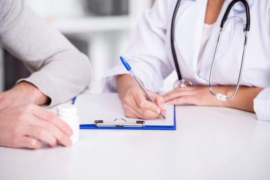Fotografía de doctora con paciente llenando un formulario con bolígrafo azul